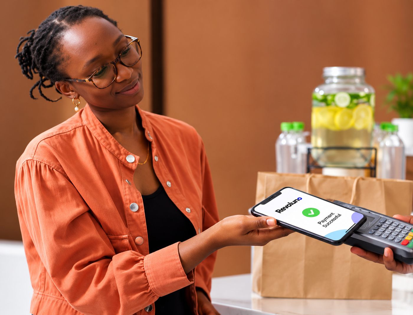 A customer pays by tapping her phone on a Revoluno card terminal at a shop counter